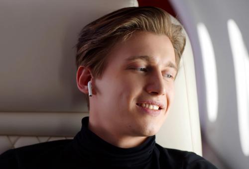 Young business jet passenger with earbuds on