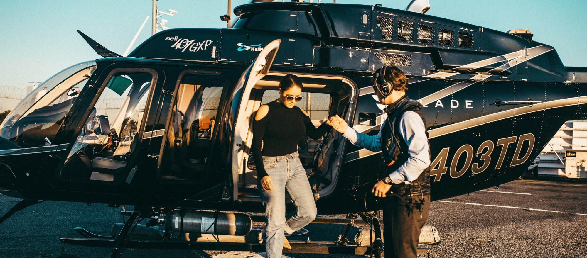 Female passenger exiting Blade helicopter with assistance from the pilot